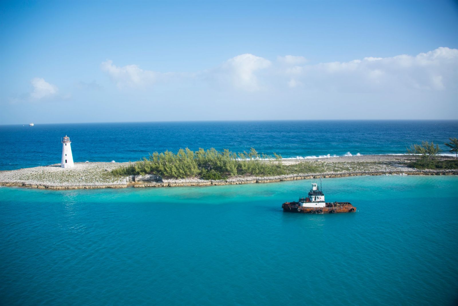 Nassau Harbour lighthouse and a tugboat in turquoise water
